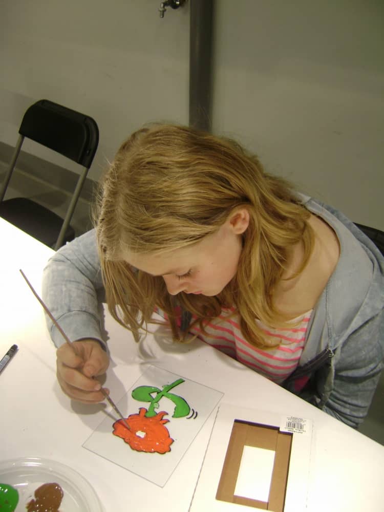 Dziewczynka malująca kwiatek na szkle.