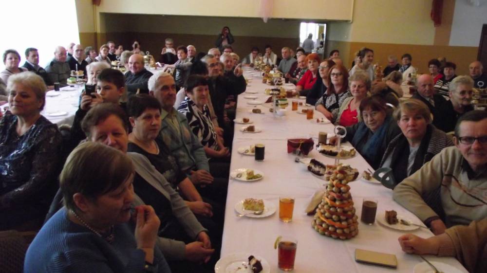 Babcie i Dziadkowie siedzący przy odświętnym stole.