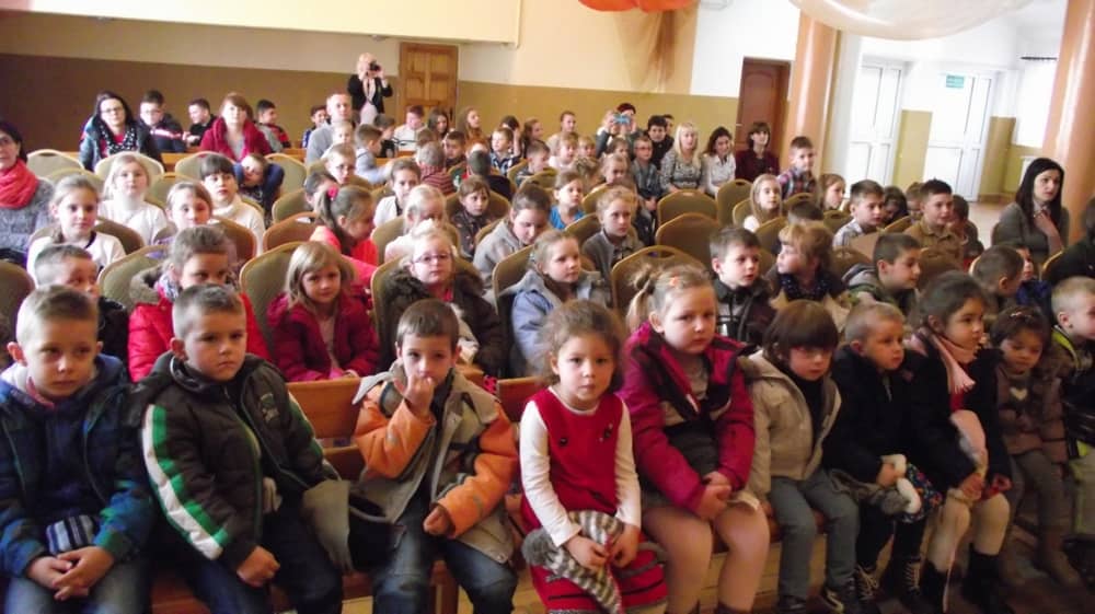 Grupa dzieci siedzących na widowni.