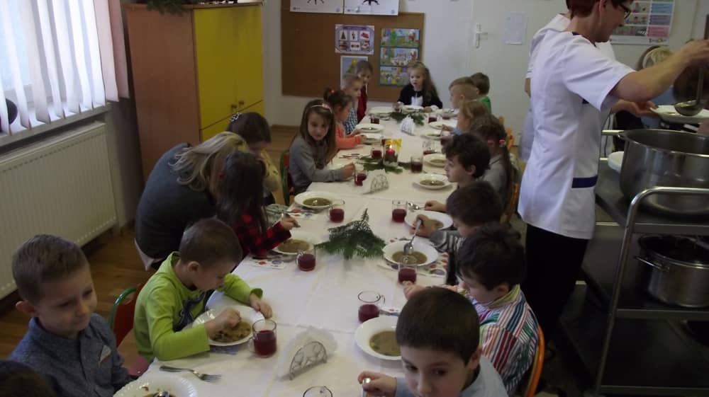 Grupa dzieci jedzących wigilijne potrawy. 