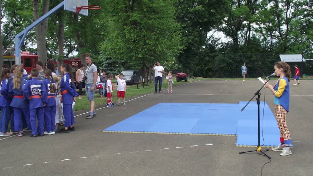 Dzieci stojące przed niebieskimi materacami. 