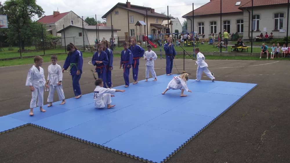 Dzieci koziołkujące po niebieskich materacach.