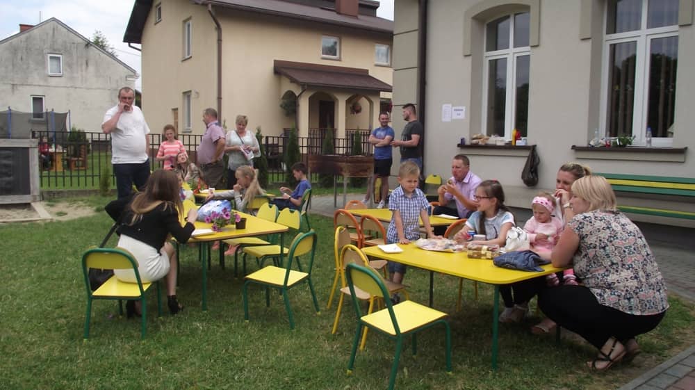 Dzieci siedzące przy żółtych stolikach.