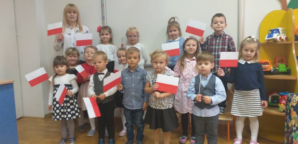Dzieci pozujące do zdjęcia, trzymające w rękach flagi Polski.